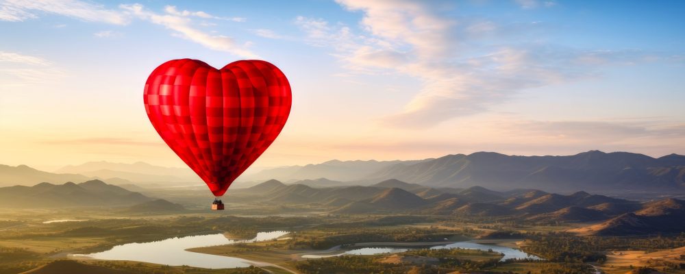 A large, red, heart-shaped balloon flies high in the clouds over the mountains at sunset. An unusual gift for a holiday, emotions, balloonists, extreme sports. A large, red, heart-shaped balloon flies high in the clouds over the mountains at sunset. An unusual gift for a holiday, emotions, balloonists, extreme sports. Valentine's day, newlyweds, engagement, birthday, wedding, anniversary, surprise, date.
